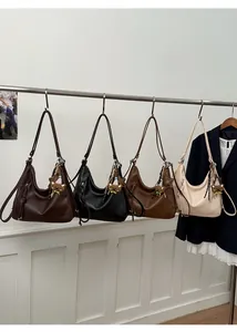 Hobo bags in four colors with bear charms hanging on a rack against a white wall