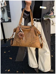 Detail der Wildleder-Einkaufstasche mit Metallnieten und Donut-Plüsch-Anhänger im Streetstyle