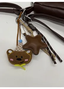 Close-up of cute plush bear and star charms with woven ropes on a brown tote bag