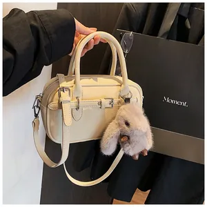 Close-up of cream square tote bag with pebble texture and cute plush bunny charm