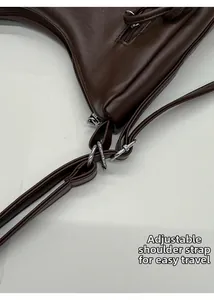 Detail of adjustable silver metal buckle and shoulder strap on dark brown leather tote bag