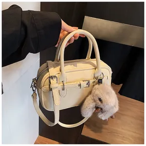 Close-up of off-white retro square bag with metal buckle and plush rabbit keychain