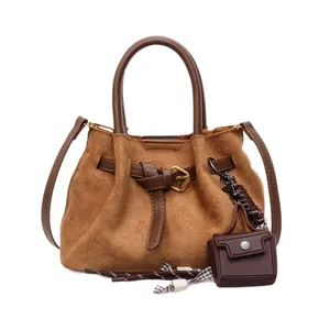 Vintage-Beuteltasche aus braunem Wildleder mit Ledergriff und Mini-Anhänger auf Weiß
