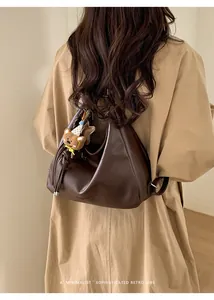 Detail of vintage brown tote bag with bear charm worn by a model in a trench coat