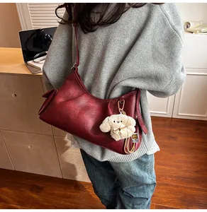 Detail view of burgundy pleat tote bag with a cute dog plush charm on the side