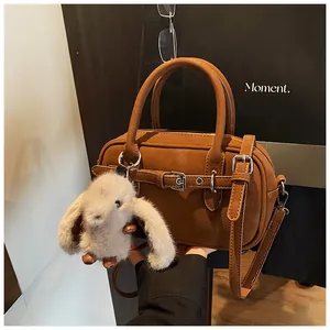 Detailed view of brown lychee grain leather handbag with cute plush bunny charm accessory