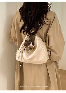 Detail view of cream hobo shoulder bag with drawstring ties and cute plush charms