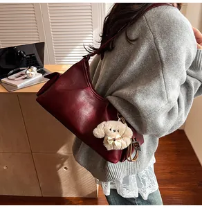 Detail of burgundy ruched shoulder bag with a cute white plush puppy charm pendant