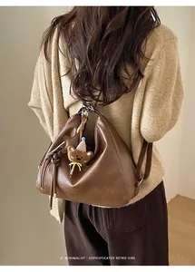 Detail of soft dark brown leather tote featuring a cute bear and star charm attachment