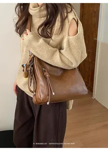 Deep brown retro tote bag with knot zipper detail shown on shoulder of a model