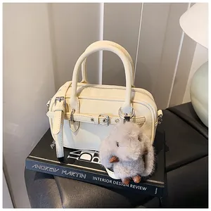 Close-up of cream leather boston bag with rabbit charm on stack of premium books