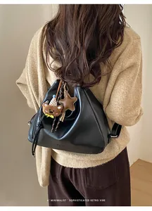 Close-up of a black matte leather crescent bag with cute bear and star charms details