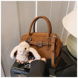 Detail of brown leather handbag with litchi texture and a cute white rabbit pendant
