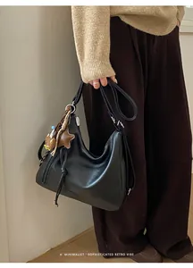 Retro black leather crescent bag with cute bear charm shown on a stylish model