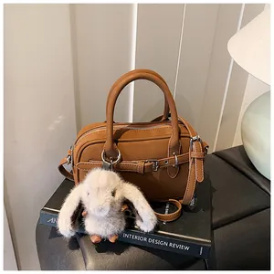 Brown leather crossbody bag with rabbit charm detail and silver buckles on the side