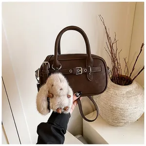 Detail of dark brown lychee texture bag with silver buckle and cute bunny charm
