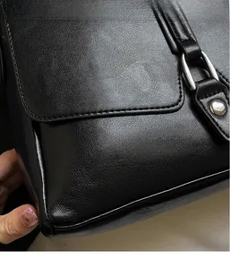 Close-up of black litchi grain leather texture and silver buckle on a crossbody bag