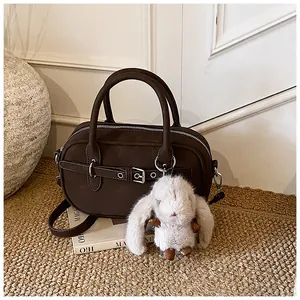 Macro shot of dark coffee retro handbag featuring silver buckle and cute plush bunny charm