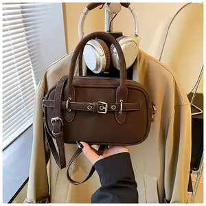 Detailed close-up of dark brown vintage leather handbag with buckle strap and handle