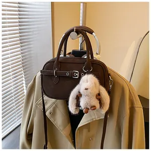 Detail of dark brown vintage crossbody bag with silver hardware and plush rabbit charm