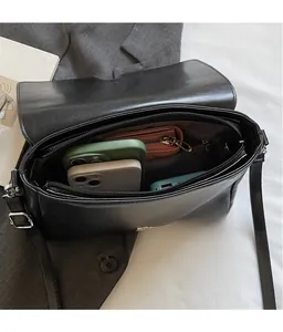 Detailed view of the spacious interior of a black leather crossbody bag with multiple items