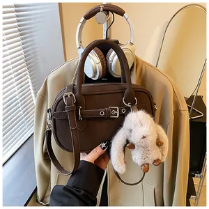 Detail of dark brown leather handbag with silver buckle and plush bunny charm