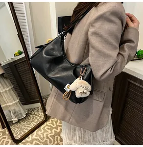 Detail of black pebbled leather hobo bag with puppy charm and elegant metal buckles