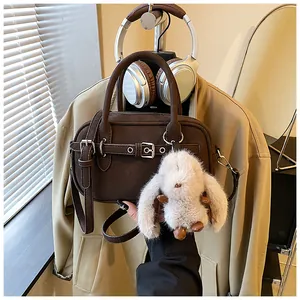 Detail of vintage brown mini Boston bag with plush rabbit charm and crossbody strap