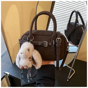 Detail view of coffee brown vintage handbag with belt buckle and cute plush rabbit charm