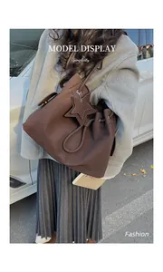 Dettaglio di una borsa tote grande marrone scuro con ciondolo a stella su outfit casual