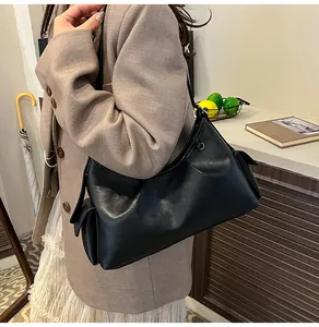 Detail view of the black pleated underarm bag showing side pockets and sleek PU leather texture