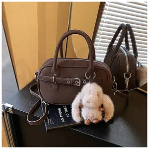 Detail of dark brown pebble leather handbag with silver buckle and plush bunny charm