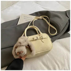 Detail of cream white lychee texture leather bag with buckle and plush rabbit charm
