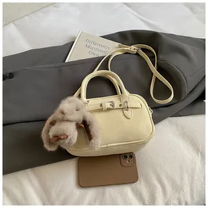 Close-up of off-white lychee grain leather handbag with cute plush rabbit charm
