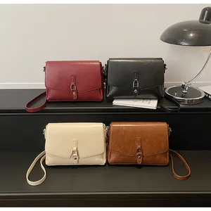 Four retro minimalist crossbody bags in wine red, black, beige, and caramel displayed on a stand