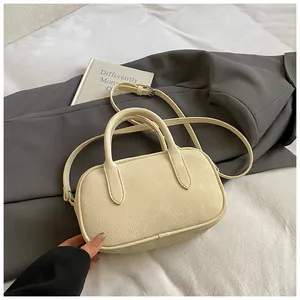 Detail shot of beige pebble grain texture and sturdy stitching on a crossbody handbag