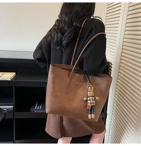 Close-up of a brown faux leather tote bag with a cute rabbit charm and golden logo detail