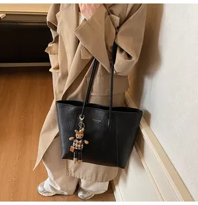 Close-up of black leather tote bag with gold logo and leopard print rabbit charm
