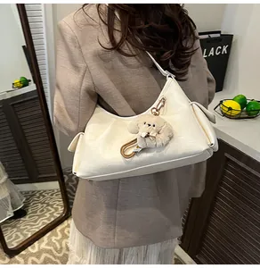 Close-up of cream leather shoulder bag with cute plush puppy charm for women