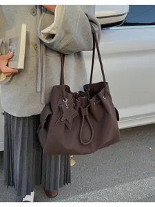 Dettaglio di una borsa tote in pelle opaca marrone scuro con coulisse e ciondolo a stella