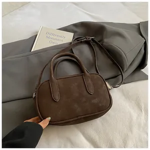 Close-up of a vintage dark brown matte crossbody bag on a textured grey blazer