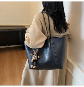 Detail of black leather tote bag with vintage matte texture and cute plush bunny charm
