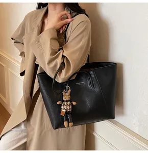 Close-up of black leather tote bag featuring golden logo and houndstooth bunny charm detail