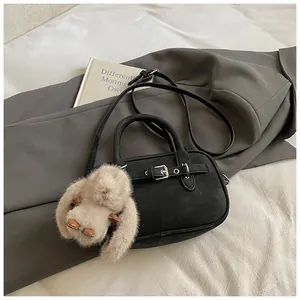 Detail of black matte leather square bag with belt buckle and cute bunny pendant