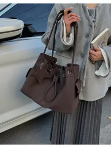 Vista in stile urban della borsa tote marrone scuro con ciondolo a stella e tasca