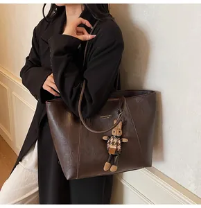 Detail of dark coffee tote bag in oil wax leather with a cute plush rabbit charm