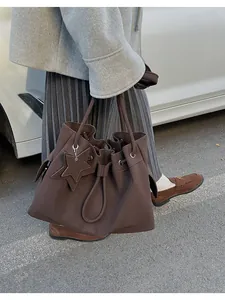 Scatto all'aperto di una grande borsa tote in pelle marrone scuro con ciondolo a stella