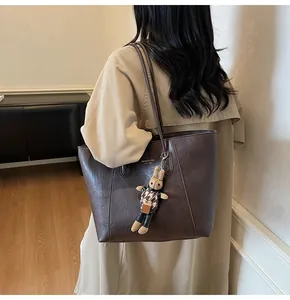 Detail of dark brown tote bag with premium leather texture and cute rabbit charm pendant