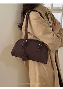 Detailed side view of a retro brown bowling shoulder bag on a trench coat