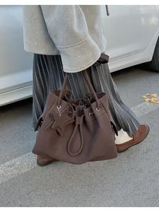 Dettaglio della borsa tote color caffè scuro con chiusura a coulisse e ciondolo